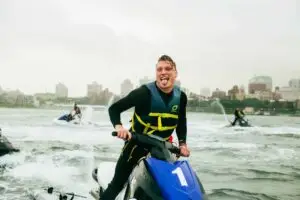 a man smiling next to a body of water