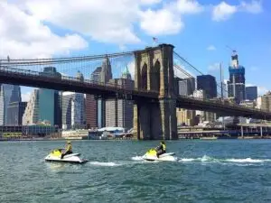 people jet skiing in front of Brooklyn bridge