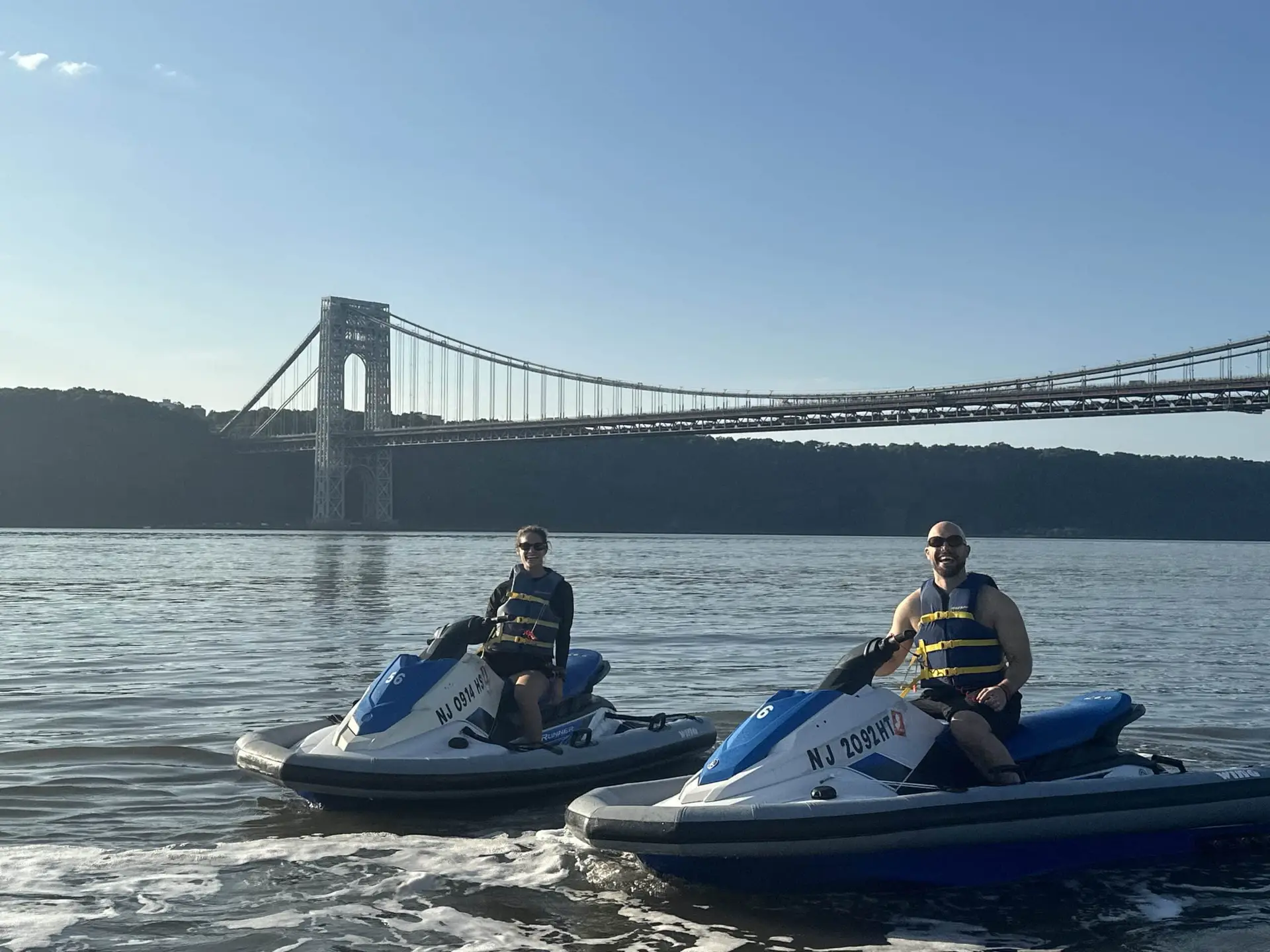 couple on jet skis in front of the brooklyn bridge