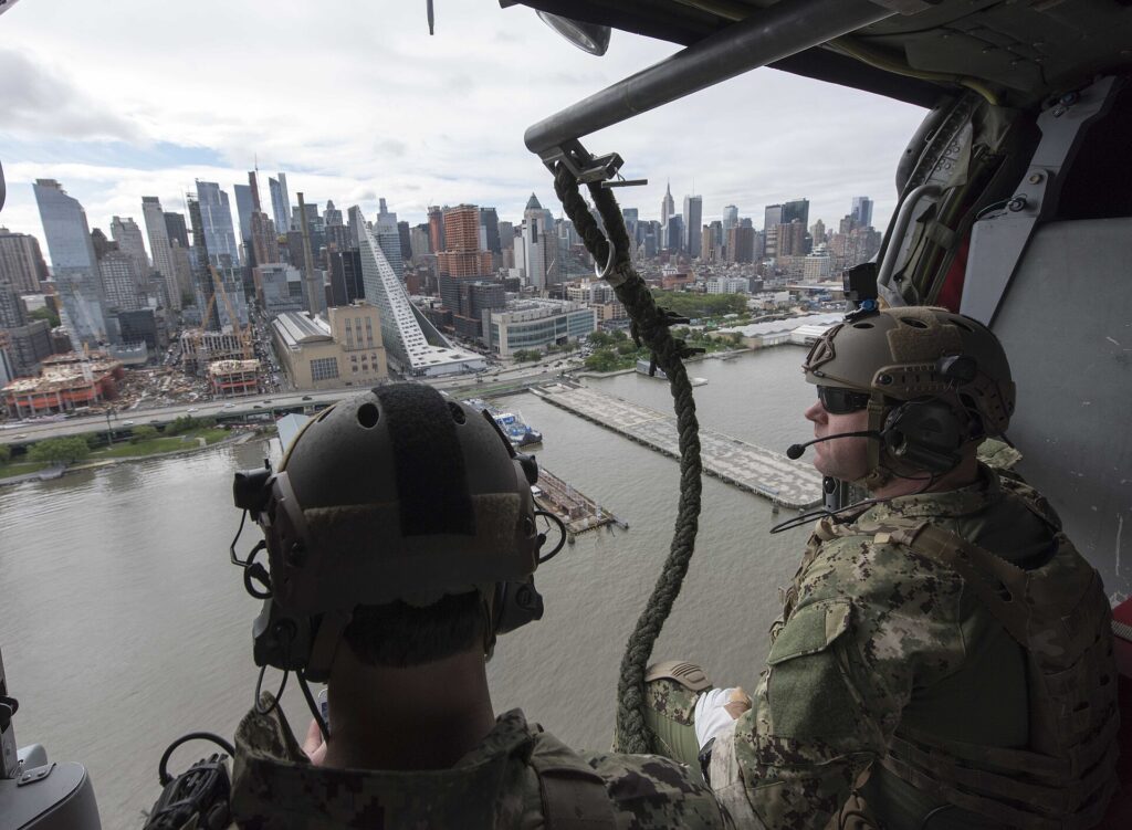 Sailors fly past the Manhattan skyline in a Navy helicopter during Fleet Week New York 2017