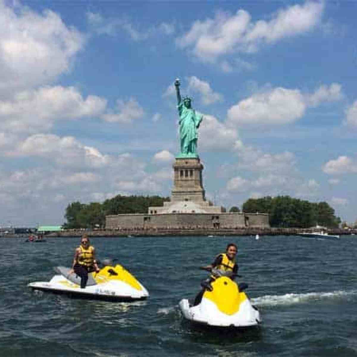 a small boat in a body of water with Statue of Liberty in the background