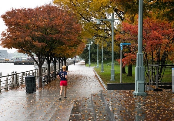 a group of people walking down a sidewalk in Hudson River Park - Manhattan