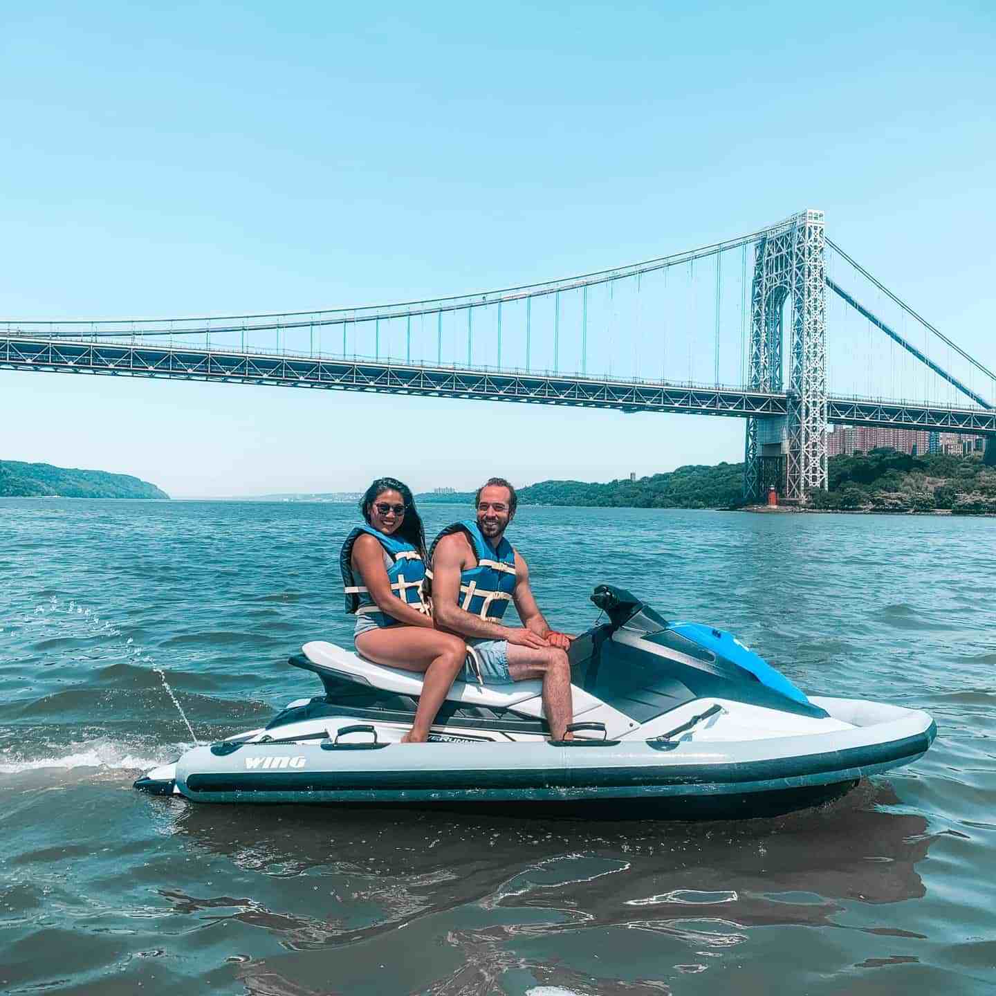 couple on a jet ski in the Hudson River in front of the Brooklyn bridge