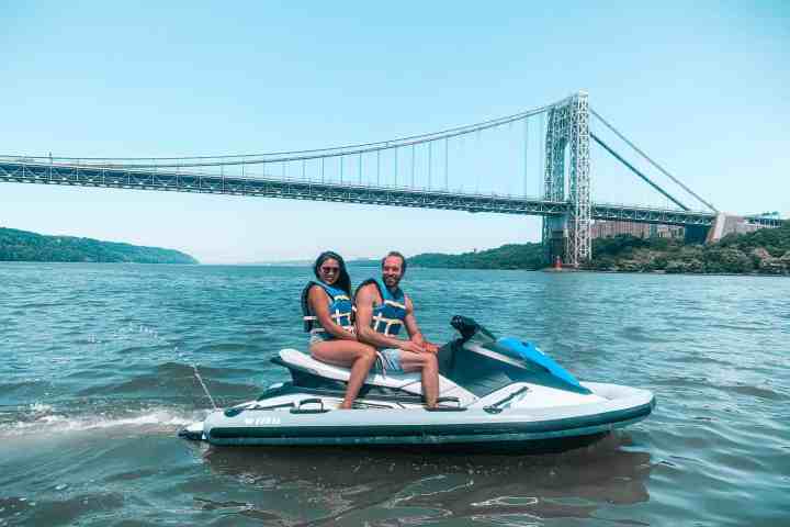 couple on a jet ski in the Hudson River in front of the Brooklyn bridge