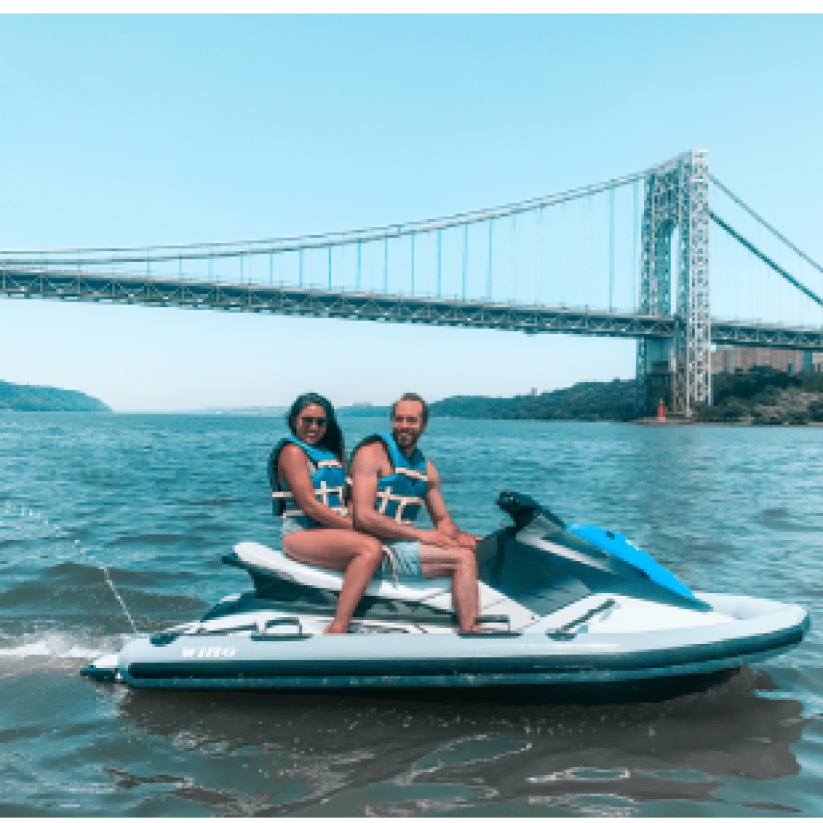 2 people riding a jet ski in front of the Brooklyn bridge