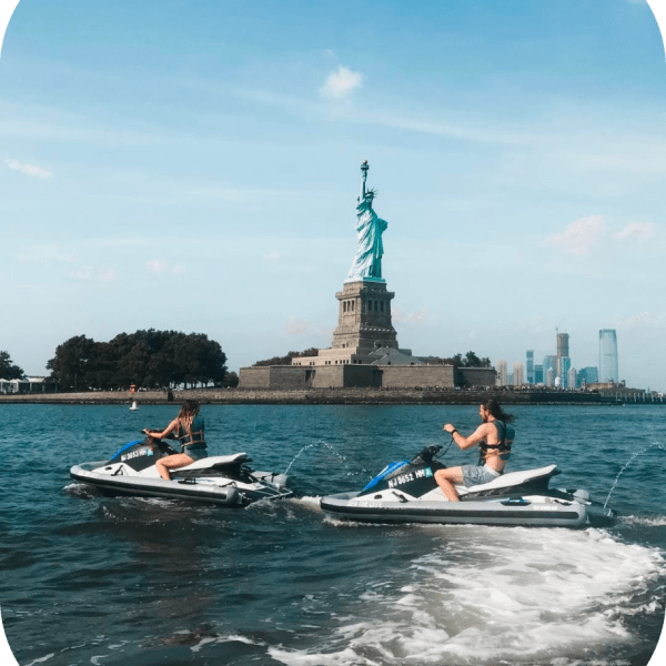 people on jet skis in front of the statue of liberty