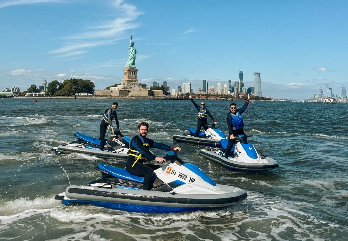 a group of people on jet skis in front of the statue of liberty