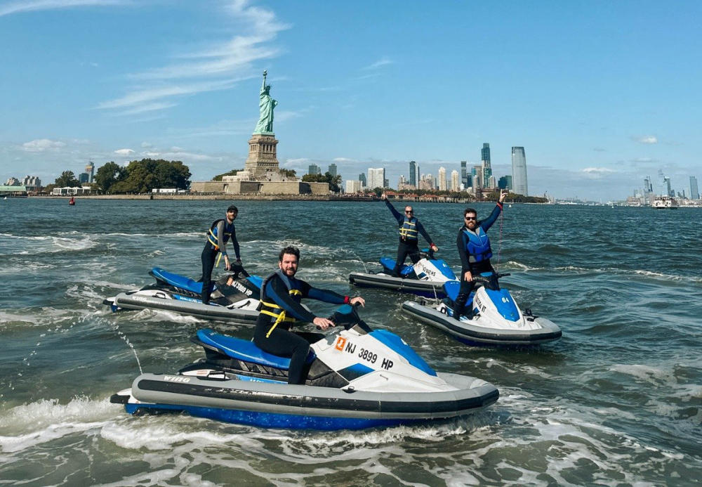 a group of people on jet skis in front of the statue of liberty