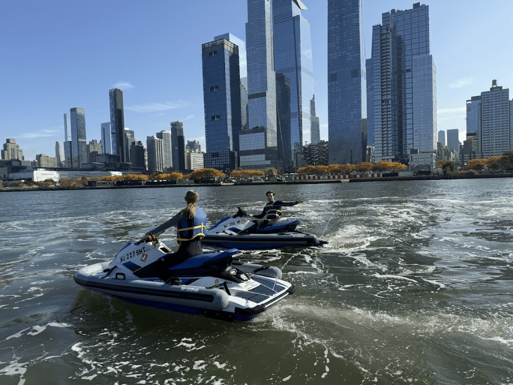 couple jet skiing with NYC skyline in background couple jet skiing with NYC skyline in background