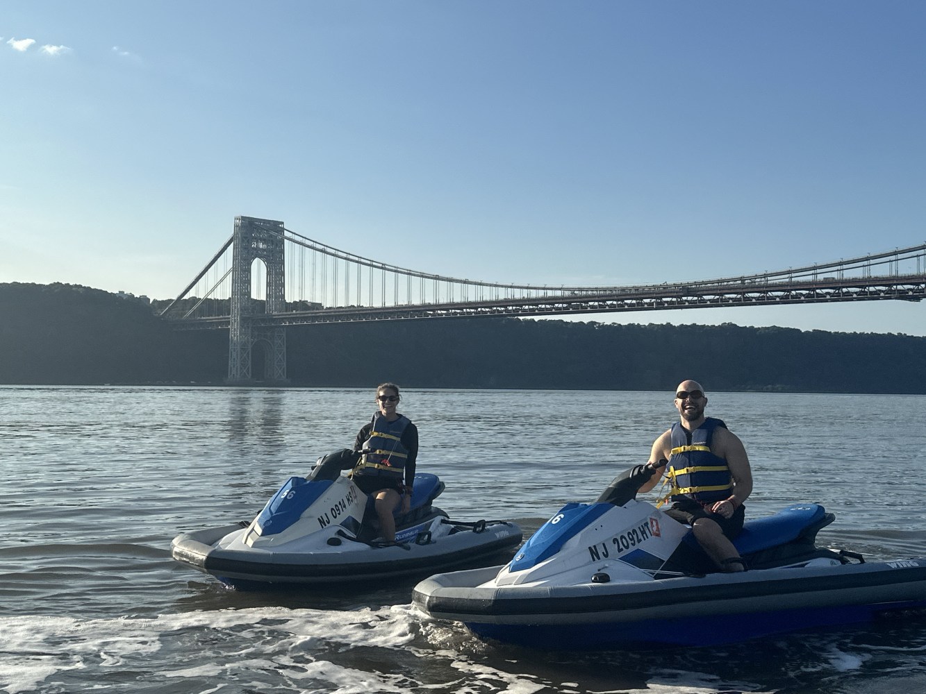 couple on jet skis in front of the Brooklyn bridge